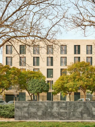 Architectural project - urban greenery, apartment facade, symmetrically placed windows, stone facade, greenery foreground, sophisticated facade, apartment block, beige facade, rhythmic pattern, vertical emphasis, property development, urban residence, linear design, urban trees, vibrant neighborhood, modern apartment, eco friendly material, city living, grey, cityscape, passive design, natural tones, contemporary architecture, sustainable architecture, green, urban planning, beige, concrete, minimalist facade, daylight optimization, public space, urban design, modern facade, landscape integration, elegant design, rectangular windows, stone, landscape design, exterior view, residential building, sustainable facade, textured facade, residential area, urban context, urban living, street view