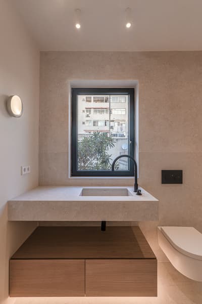 Architectural project - refined style, muted palette, recessed lighting, wood vanity, minimalist bathroom, compact bathroom, beige bathroom, wall-mounted sink, floating vanity, minimalist faucet, contemporary look, eco-friendly design, sustainable materials, wood, city living, natural light, neutral tones, daylight, beige, light wood, black, clean lines, white, window view, stone, stone flooring, integrated lighting, sleek design, plaster walls, modern bathroom, understated elegance, seamless design, urban view, urban apartment