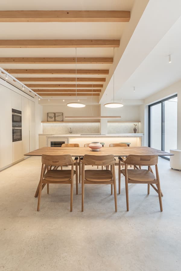 Architectural project - beige walls, streamlined design, dining room, wooden chairs, dining chairs, beige floor, pendant lights, warm space, warm interior, sustainable materials, wood, timber, relaxed vibe, natural light, warm tones, modern vibe, neutral tones, exposed beams, daylight, beige, light wood, eco friendly, Scandinavian style, minimalist design, contemporary home, clean lines, white walls, large windows, indoor outdoor, white, Nordic style, energy efficient, timber ceiling, airy space, open layout, dining area, wooden table, dining table, inviting space, cozy atmosphere, modern home, modern kitchen, simple decor, comfortable living, wood ceiling, open space, Japandi, kitchen, minimalist shelves, airy kitchen