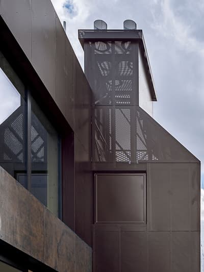 Architectural project - modern building, minimal facade, metal cladding, metallic finish, industrial facade, ventilation system, low maintenance, urban aesthetic, urban integration, city development, architectural detail, steel, metal, contemporary architecture, innovative design, grey, neutral tones, modern construction, steel structure, urban design, geometric design, industrial chic, sustainable building, minimalist exterior, sleek design, facade texture, modern exterior, facade rhythm, dark tones, dark facade, eco facade, urban facade