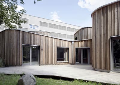 Architectural project - natural materials, wood, timber, raw materials, grey, outdoor space, passive design, sustainable design, warm tones, contemporary architecture, neutral tones, beige, wood facade, timber facade, exterior design, light wood, daylight optimization, Scandinavian influence, timber construction, honey wood, natural textures, minimalist design, tranquil setting, biophilic design, natural ventilation, timber cladding, wood cladding, modern architecture, textured wood, inviting space, garden view, eco-friendly building, green design, exterior wood, wooden deck, educational space, school building, light facade, public building, circular shapes, curved design, courtyard, timber decking, educational architecture, architectural rhythm