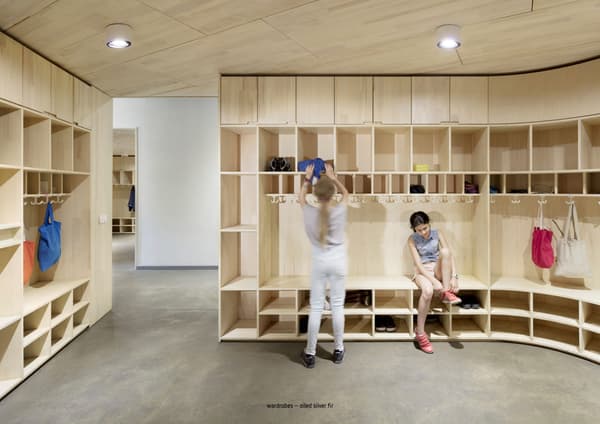 Architectural project - minimal design, natural materials, sustainable materials, wood, sustainable design, modular design, eco design, community space, neutral tones, functional space, multi-use space, plywood, beige, light wood, functional design, eco friendly, modern design, Scandinavian style, light tones, clean lines, Nordic design, warm ambiance, wood shelves, inviting space, earthy tones, built-in shelves, bright space, interior design, educational space, hallway, practical design, wardrobe, shelving, storage unit, timber storage, wood storage, shelving unit, wooden shelves, plywood interior, Scandinavian interior, modern interior, organized space, contemporary space, interior architecture, school interior, children's space, educational interior, coat hangers, bags, open shelving, wooden finish, smooth finish, light finishes, circularity, modern wood