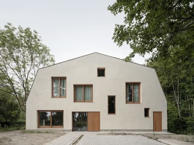 Architectural project - beige facade, geometric shape, traditional meets modern, modern countryside, plaster facade, serene vibe, natural materials, wood, sustainable design, warm tones, natural tones, eco design, outdoor area, neutral tones, beige, natural wood, serene atmosphere, minimalist design, neutral colors, passive house, modern facade, clean lines, large windows, rectangular windows, eco friendly home, harmonious design, countryside home, wood frame, energy efficient, timber accents, plaster, woodland setting, quiet retreat, nature integration, residential home, private residence, minimalist aesthetic, contemporary house, green surroundings, architectural elegance, low carbon building, light beige