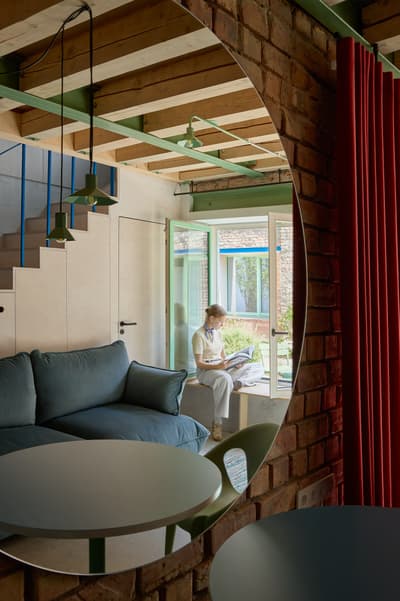 Architectural project - green accents, brick wall, vintage touch, raw textures, exposed brick, pendant lighting, wooden steps, loft vibe, spacious room, modern retro, blue sofa, staircase design, open beams, convivial atmosphere, intimate space, natural materials, serene environment, wood, timber, natural light, glass, neutral tones, beige, functional design, blue, rustic modern, Scandinavian style, neutral palette, calming space, glass doors, pastel green, tranquil setting, modern rustic, eco home, light filled, indoor outdoor, Nordic design, inviting home, energy efficient, timber ceiling, casual living, minimalist decor, earthy tones, warm atmosphere, brick, residential design, cozy corner, red brick, garden view, reading nook, comfortable seating, built-in seating, wood ceiling, family room, structural elements, relaxed space, sustainable living, cozy living room, home retreat, timber steps, red