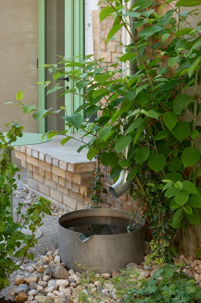 Architectural project - brick wall, potted plants, plants, garden decor, airy vibe, small garden, outdoor garden, recycled bricks, green doors, renovation project, exterior renovation, pebble ground, stone ground, stone textures, sustainable garden, serene bench, modern garden, rustic elements, urban transformation, vibrant plants, soothing corner, natural materials, steel, metal, outdoor space, sustainable architecture, green, beige, brown, eco friendly, urban oasis, casual seating, relaxation spot, ecological design, earth tones, biophilic design, stone, rustic style, inviting space, brick, tranquil vibe, garden retreat, cozy corner, brick facade, greenery, nature integration, water feature, peaceful atmosphere, urban garden