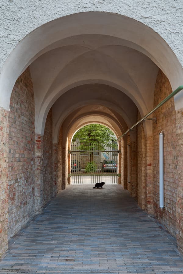 Architectural project - outdoor walkway, brickwork, transitional space, exposed brick, brick walls, old-world charm, curved ceiling, quiet space, rustic corridor, masonry, stone paving, arched passageway, historical architecture, archway, rustic brick, alleyway, light corridor, courtyard entrance, arched entry, architectural arch, European style, urban passage, pedestrian path, cobblestone walkway, private alley, quaint alley, timeless architecture, conserved structure, soothing light, outdoor passage, gateway, urban history, Europe-inspired, natural light, neutral tones, beige, serene atmosphere, stone, traditional design, rustic ambiance, brick, red brick, heritage building, textured walls, urban architecture, urban retreat, brick texture, vaulted ceiling, red