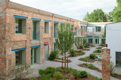 Architectural project - terrace, native plants, urban renewal, brickwork, exposed brick, industrial look, open air space, urban courtyard, masonry, recycled brick, multi-family housing, shared courtyard, eco-friendly architecture, communal area, social housing, eco-conscious living, revitalization project, light gray, natural materials, metal, outdoor space, natural light, outdoor living, passive design, sustainable design, glass, neutral tones, daylight, industrial vibe, urban oasis, rustic charm, low carbon footprint, green architecture, modern rustic, residential development, green living, earthy tones, brick, landscape design, brick facade, red brick, greenery, garden view, green design, seating area, fresh air, garden path, biodiversity, community housing, green roof, environment friendly