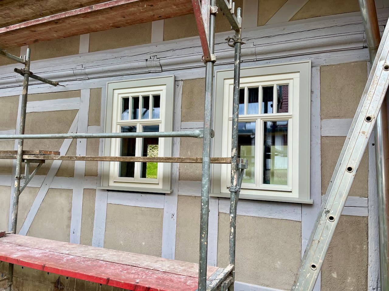 Architectural project - charming exterior, building renovation, restoration project, period architecture, grey wall, traditional materials, wooden windows, historical building, European architecture, classic style, exterior renovation, heritage restoration, symmetrical facade, detailed craftsmanship, sustainable materials, wood, timber, scaffolding, grey, construction site, beige, rural architecture, plaster wall, plaster, traditional architecture, vernacular design, countryside house, rustic exterior, timber framing, soft tones, sustainable renovation