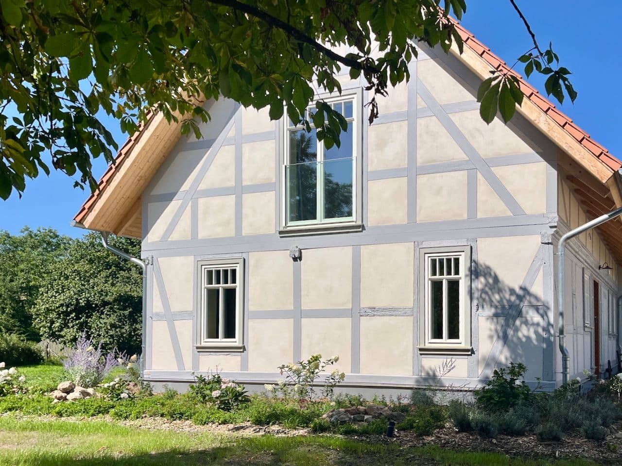 Architectural project - quaint home, lush setting, landscaped garden, cottage, classic design, farmhouse, idyllic setting, historic style, half-timbered house, German style, natural materials, wood, timber, outdoor space, timber frame, natural tones, grey, serene atmosphere, natural landscape, white facade, white, cozy vibe, inviting home, countryside home, timber accents, plaster, pitched roof, traditional architecture, plaster finish, rustic facade, traditional craftsmanship, greenery, garden view, gable roof, countryside living, green surroundings, rural house, rural retreat