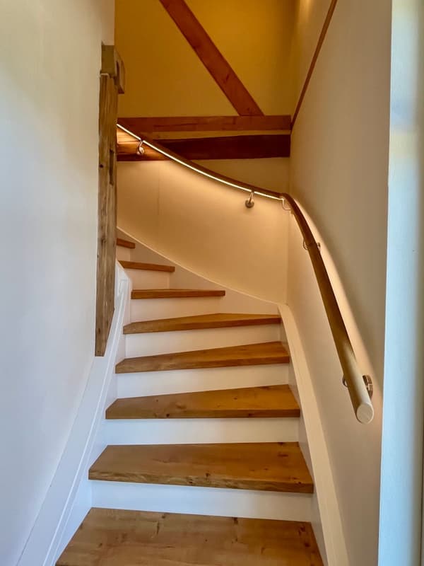 Architectural project - home staircase, cozy light, minimal design, intimate space, indoor space, natural materials, wood, timber, natural light, sustainable design, exposed beams, beige, brown, functional design, eco friendly, simple design, rustic vibe, wood beams, Scandinavian style, timber floor, neutral palette, wood floor, modern rustic, inviting home, comfortable home, relaxed living, earthy tones, warm atmosphere, rustic design, natural texture, traditional touch, residential space, nordic influence, home interior, open space, timber railing, wooden stairs, warm lighting, hallway, interior architecture, wooden finish, home renovation, staircase, timber steps, stairwell