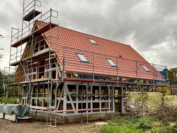 Architectural project - skylights, rustic materials, red tiles, terracotta roof, farmhouse, rooftop, framework, wood, timber, scaffolding, outdoor space, timber frame, natural light, eco design, grey, neutral tones, timber structure, under construction, construction process, building site, brown, open structure, wooden beams, rural architecture, natural textures, open framework, exterior, low carbon, circular design, sustainable home, passive house, landscape integration, Nordic style, countryside home, energy efficient, stone, rustic style, sloped roof, pitched roof, terracotta, stone wall, rural setting, traditional style, earthy palette, renovation, rural house, clay tiles, red, remodel