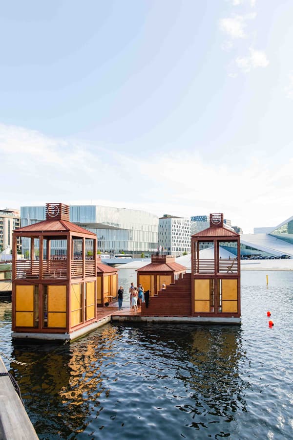 Architectural project - unique venue, natural integration, waterfront, floating structure, water pavilion, timber pavilion, urban waterscape, open deck, terrace design, architectural landmark, steel accents, water reflection, floating architecture, cityscape backdrop, urban waterfront, circular economy, cultural space, sustainable materials, wood, timber, relaxation area, steel, outdoor living, passive design, sustainable design, glass, modular construction, contemporary architecture, innovative design, neutral tones, gathering space, recreational area, beige, brown, modern design, urban oasis, leisure space, minimalist design, public space, event space, social hub, geometric design, modern pavilion, wood structure, panoramic view, social gathering, eco architecture, outdoor retreat, architectural innovation