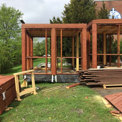Architectural project - modular architecture, assembly, prefabricated, prefab, unfinished, frame assembly, timber project, building outdoors, ecological building, timber materials, natural materials, wood, timber, outdoor space, eco design, sustainable architecture, green, neutral tones, construction phase, construction site, modern construction, adaptable design, outdoor construction, brown, timber facade, eco friendly, natural setting, timber construction, open framework, modular building, building process, eco construction, wood panels, timber assembly, passive house, landscape integration, wood framing, energy efficient, greenery, green design, wooden structure, structural elements, innovative architecture