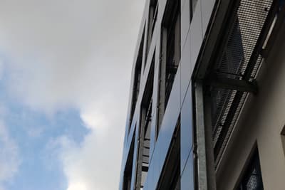 Architectural project - facade, vertical lines, clouds, sunlight reflection, metal structure, exterior facade, urban skyline, passive solar design, grid pattern, sleek facade, structural frame, architectural detail, industrial design, steel, sustainable design, glass, grey, neutral tones, urban environment, city architecture, building facade, blue, glass panels, minimalist design, urban design, blue sky, geometric design, modern aesthetics, modern facade, white, structural element, reflective surface, sky view, urban architecture, facade texture, modern urban, eco facade, contemporary building, high-rise building