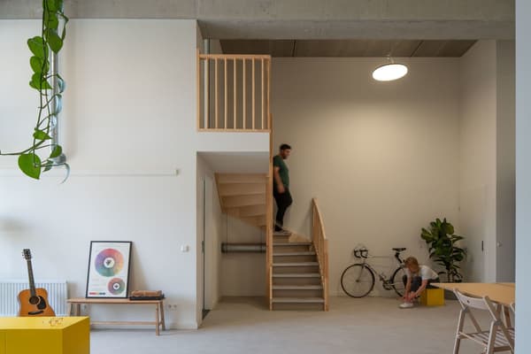Architectural project - exposed concrete, concrete ceiling, modern loft, functional decor, plant decor, loft interior, pendant lighting, decorative wall, bike storage, warm interior, natural materials, wood, timber, natural light, multifunctional area, neutral tones, daylight, beige, concrete, Scandinavian style, minimalist style, neutral palette, minimalist design, casual seating, social space, informal setting, casual space, playful elements, creative space, white walls, white, eco friendly home, cozy vibe, Nordic style, energy efficient, small space, open plan, earthy tones, greenery, bright interior, compact living, wooden staircase, sustainable living, indoor plants, relaxed home, timber steps, double height, urban apartment