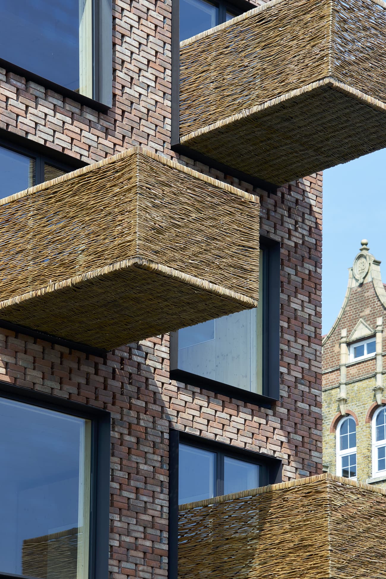 Architectural project - natural materials, architectural design, eco-friendly design, sustainable materials, wood, outdoor space, warm tones, contemporary architecture, innovative design, city architecture, exterior design, natural textures, industrial touch, neutral colors, urban design, geometric design, modern facade, architectural details, earthy tones, exterior elements, brick, brick facade, red brick, residential building, balcony design, textured facade, urban architecture, modern exterior, exterior pattern, urban facade, brick building, city dwelling, urban living, woven texture, woven elements, woven balconies, modern residential, brickwork pattern, unique balconies, high-rise building, modern materials, basket weave, structural grid, pattern play, open balconies, woven materials