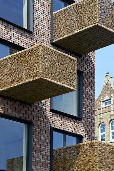 Architectural project - natural materials, architectural design, eco-friendly design, sustainable materials, wood, outdoor space, warm tones, contemporary architecture, innovative design, city architecture, exterior design, natural textures, industrial touch, neutral colors, urban design, geometric design, modern facade, architectural details, earthy tones, exterior elements, brick, brick facade, red brick, residential building, balcony design, textured facade, urban architecture, modern exterior, exterior pattern, urban facade, brick building, city dwelling, urban living, woven texture, woven elements, woven balconies, modern residential, brickwork pattern, unique balconies, high-rise building, modern materials, basket weave, structural grid, pattern play, open balconies, woven materials