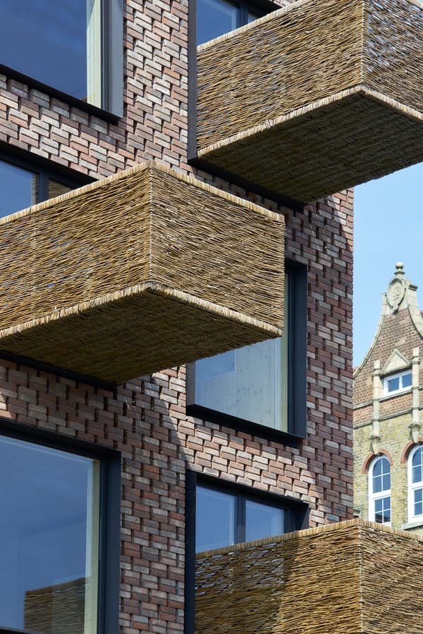 Architectural project - natural materials, architectural design, eco-friendly design, sustainable materials, wood, outdoor space, warm tones, contemporary architecture, innovative design, city architecture, exterior design, natural textures, industrial touch, neutral colors, urban design, geometric design, modern facade, architectural details, earthy tones, exterior elements, brick, brick facade, red brick, residential building, balcony design, textured facade, urban architecture, modern exterior, exterior pattern, urban facade, brick building, city dwelling, urban living, woven texture, woven elements, woven balconies, modern residential, brickwork pattern, unique balconies, high-rise building, modern materials, basket weave, structural grid, pattern play, open balconies, woven materials