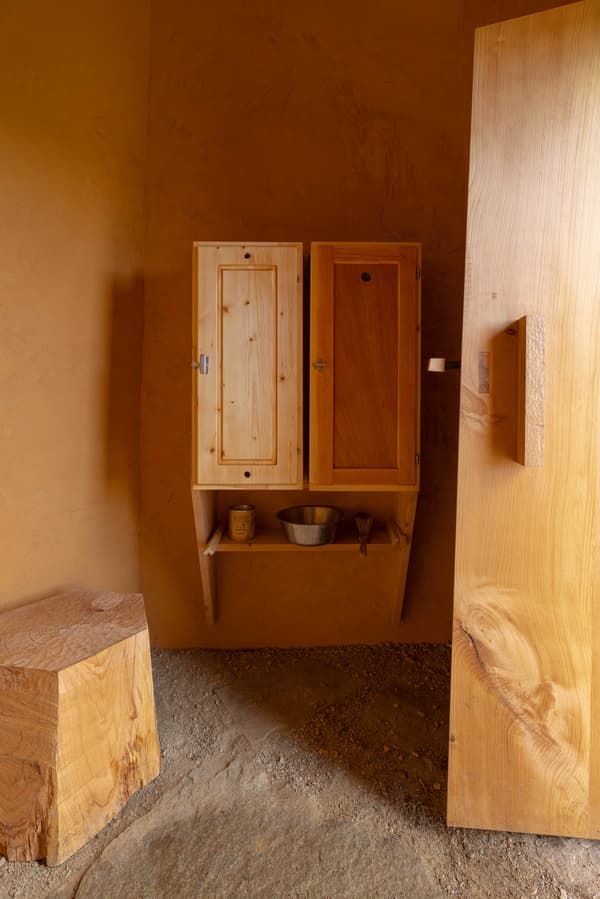 Architectural project - rustic interior, clay color, homely feel, wood grains, timber stool, small shelf, artisanal style, rugged aesthetic, cottagecore, boho style, hand-built, organic style, warm interior, natural materials, sustainable materials, wood, timber, natural light, warm tones, beige, brown, eco friendly, compact space, simple design, rustic charm, minimalist design, raw texture, natural palette, cozy vibe, plaster, earthy tones, clay, handcrafted, plaster finish, natural environment, wooden furniture, clay wall, understated elegance, wooden shelves, rustic decor, timber door