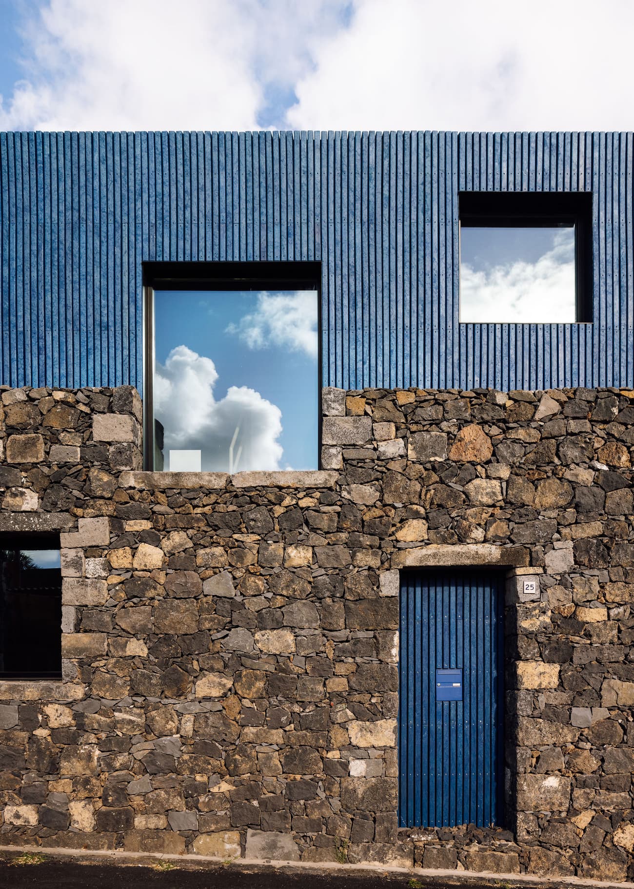 Architectural project - stone facade, natural stone, exterior contrast, minimalist house, blue cladding, basalt stone, basalt, textured stone, textured cladding, geometric windows, smooth texture, glazed windows, rustic elegance, dark stone, volcanic stone, black tones, climate responsive, natural materials, grey tones, blue tones, passive design, urban landscape, sustainable architecture, grey, exterior wall, low carbon design, blue, eco friendly, modern design, facade detail, Scandinavian style, black, natural finish, contemporary home, large windows, modern architecture, Nordic style, energy efficient, rough texture, stone wall, minimalist exterior, vertical cladding, facade design, modern exterior, architectural harmony, architectural rhythm, architectural contrast, urban home, reflective glass, residential facade, square windows, eco facade, stone texture