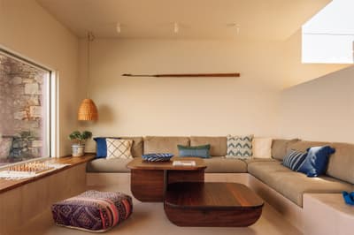 Architectural project - beige walls, lounging area, home comfort, corner sofa, wooden coffee table, woven pendant, boho chic, patterned cushions, decorative throw, pouf, chess board, tranquil ambiance, woven textures, indoor space, natural materials, relaxed vibe, natural light, bohemian style, warm tones, beige, brown, blue, sunlight, intimate setting, casual setting, neutral palette, minimalist design, relaxation spot, soft textures, modern rustic, inviting home, family space, earthy tones, Mediterranean style, cozy atmosphere, comfortable seating, bright interior, built-in seating, minimal decor, cozy living room, contemporary living