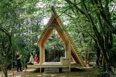 Architectural project - natural materials, wood, timber, timber frame, natural light, outdoor living, passive design, sustainable design, warm tones, green building, community space, neutral tones, daylight, gathering space, landscape architecture, light wood, open structure, eco structure, simple design, wood beams, rustic charm, minimalist design, social space, wooden pavilion, outdoor seating, eco-friendly structure, pitched roof, forest setting, triangular roof, tranquil vibe, nature connection, nature retreat, peaceful retreat, natural environment, forest shelter, pavilion design, outdoor shelter, airy pavilion, woodland hideaway, serene setting, surrounding trees, woodland scene, outdoor architecture