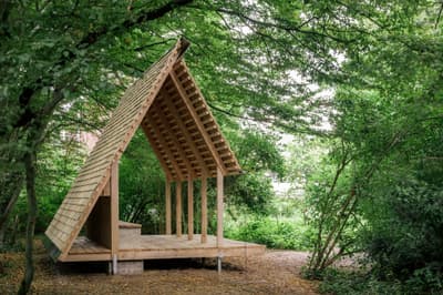 Architectural project - intimate space, natural materials, wood, timber, raw materials, natural light, outdoor living, sustainable design, timber structure, green, beige, brown, eco friendly, simple design, serene atmosphere, minimalist retreat, Scandinavian style, wooden pavilion, Nordic inspiration, green architecture, modern rustic, timber cladding, architectural simplicity, earthy tones, pitched roof, environmental design, forest retreat, timber deck, biophilic architecture, integrated nature, peaceful vibe, minimalist cabin, rustic shelter, nature hideaway, eco shelter, open air, wood slats, small pavilion, wilderness escape, woodland cabin, nature immersion, calm retreat, natural construction, forest cabin, outdoor refuge