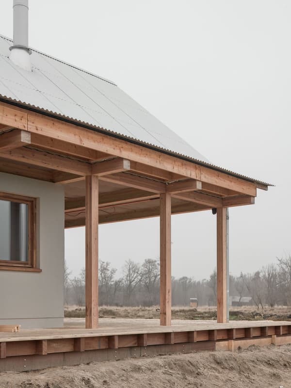 Architectural project - modern farmhouse, quiet setting, veranda, natural materials, wood, metal, outdoor space, outdoor living, passive design, sustainable design, warm tones, corrugated roof, grey, neutral tones, structural timber, beige, brown, wood facade, timber facade, natural wood, rural architecture, simple design, serene atmosphere, minimalist architecture, minimalist design, eco materials, wood structure, modern rustic, open landscape, eco home, natural ventilation, metal roof, clean lines, timber cladding, wood cladding, timber house, countryside home, landscape view, pitched roof, rural setting, exterior view, country vibe, earthy palette, gabled roof, inviting exterior, rural house