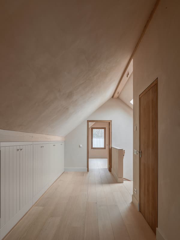 Architectural project - cozy hallway, subtle elegance, loft space, attic renovation, built-in cabinets, roof window, white cabinets, hidden storage, natural materials, wood, natural light, neutral tones, daylight, beige, light wood, peaceful setting, contemporary design, Scandinavian style, timber floor, minimalist design, serene space, relaxed atmosphere, warm wood, timber elements, clean lines, white, small window, warm ambiance, warm colors, earthy feel, residential design, Nordic vibe, textured walls, bright interior, interior, simple decor, plaster walls, wood flooring, modern interior, sloped ceiling, home hallway