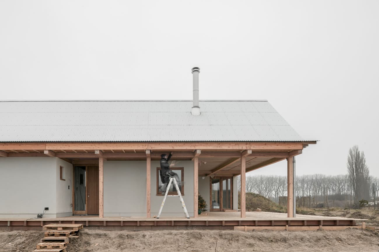 Architectural project - minimal facade, modern farmhouse, contemporary rural, wood columns, porch, natural materials, serene environment, wood, timber, steel, metal, outdoor space, passive design, warm tones, grey, neutral tones, timber structure, beige, light wood, natural setting, rural architecture, simple design, wood beams, neutral palette, raw wood, wood structure, eco home, metal roof, landscape view, energy efficient, rural living, sloped roof, rustic design, cozy atmosphere, exterior view, gable roof, sustainable house, wooden deck, insulation, rural house, countryside setting, country home
