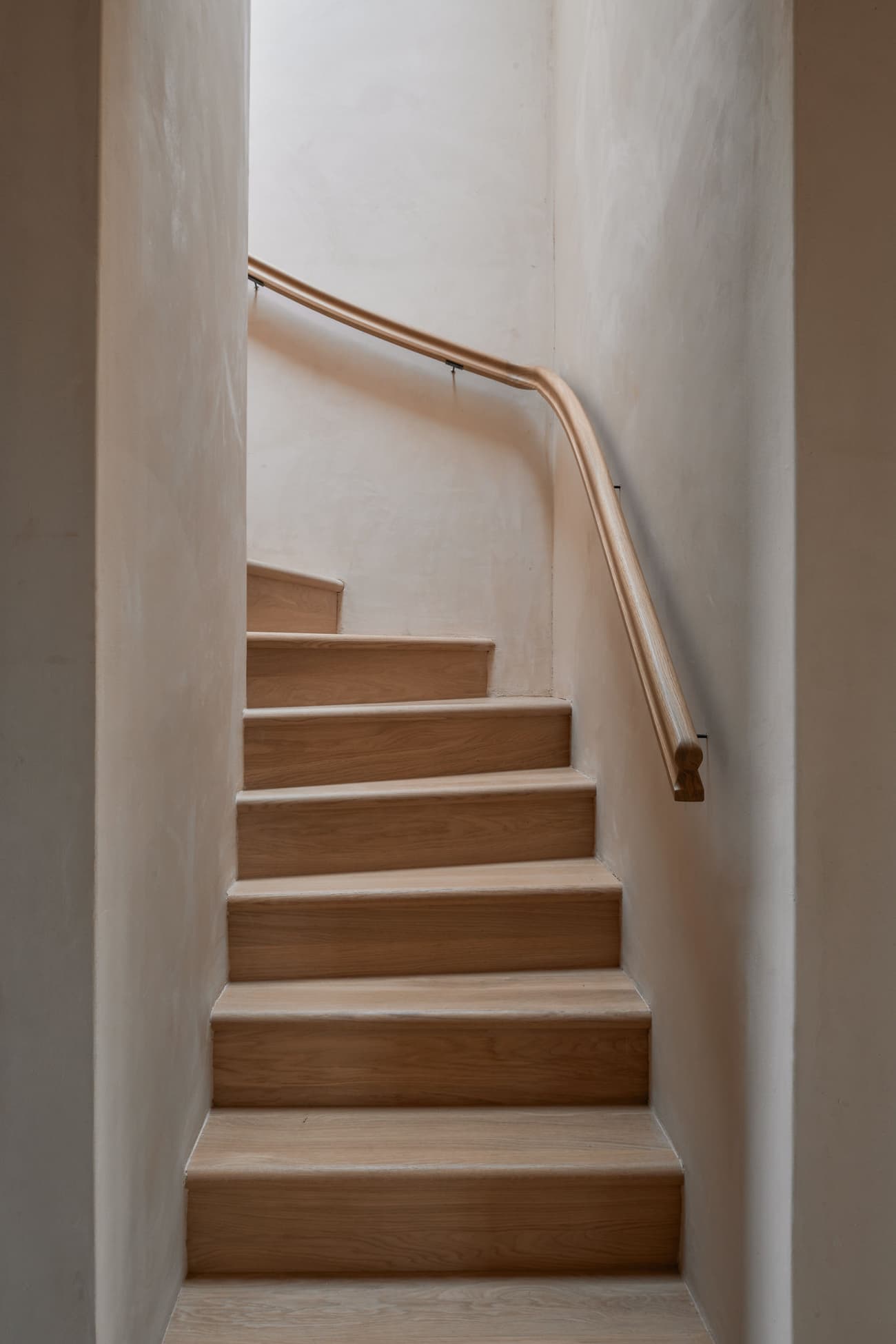Architectural project - minimalist stairs, subtle design, oak wood, timber stairs, matte finish, intimate space, natural materials, architectural detail, soft lighting, serene environment, eco-friendly design, timber, warm tones, neutral tones, beige, light wood, functional design, compact space, simple design, peaceful setting, minimalist style, calming space, sustainable home, simple elegance, Nordic design, cozy vibe, inviting home, plaster, warm atmosphere, natural texture, textured walls, warm light, Scandinavian design, plaster walls, soft tones, home interior, oak, wooden stairs, clean design, smooth finish, Japandi style, staircase, residential interior