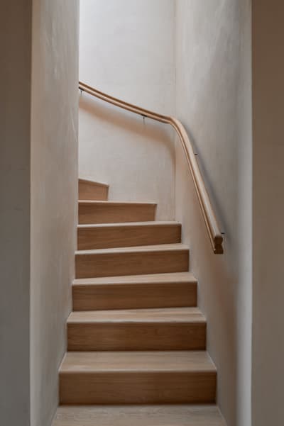 Architectural project - minimalist stairs, subtle design, oak wood, timber stairs, matte finish, intimate space, natural materials, architectural detail, soft lighting, serene environment, eco-friendly design, timber, warm tones, neutral tones, beige, light wood, functional design, compact space, simple design, peaceful setting, minimalist style, calming space, sustainable home, simple elegance, Nordic design, cozy vibe, inviting home, plaster, warm atmosphere, natural texture, textured walls, warm light, Scandinavian design, plaster walls, soft tones, home interior, oak, wooden stairs, clean design, smooth finish, Japandi style, staircase, residential interior