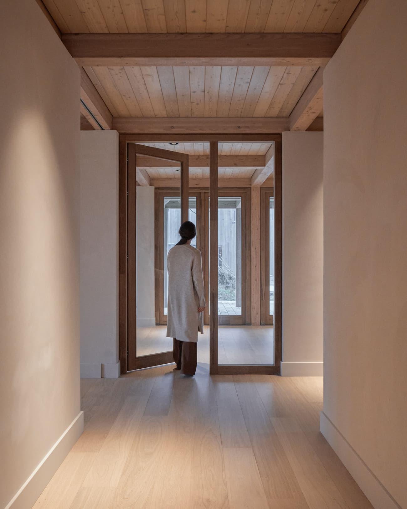 Architectural project - open door, calm space, light wood floor, simplicity, indoor space, architectural detail, wood, timber, natural light, sustainable design, glass, warm tones, neutral tones, daylight, beige, light wood, modern aesthetic, eco friendly, timber construction, timber beams, natural textures, contemporary design, Scandinavian style, neutral palette, minimalist design, eco home, clean lines, Nordic style, earthy materials, plaster, wooden interior, inviting space, cozy atmosphere, residential design, tranquil vibe, minimalist space, modern home, glass door, plaster walls, wood ceiling, pivot door, interior space, serene interior, corridor, hallway