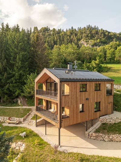 Architectural project - solar panels, elevated home, panoramic windows, natural materials, wood, timber, outdoor space, outdoor living, glass, warm tones, sustainable architecture, green, neutral tones, beige, brown, wood facade, daylight optimization, rustic modern, Scandinavian style, minimalist design, eco materials, tranquil setting, raw timber, natural landscape, biophilic design, sustainable home, passive house, hillside house, timber cladding, wood cladding, eco friendly home, timber house, energy efficient, open plan, nature retreat, forest view, green design, countryside living, countryside house, wooden textures, compact living, renewable energy, rural house, modern cabin, rural retreat