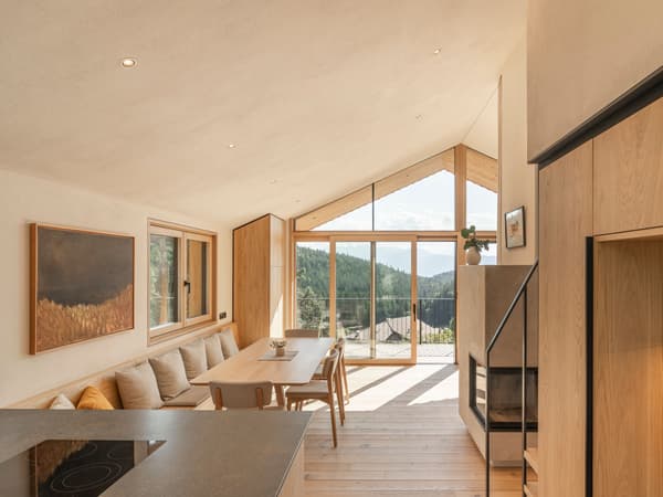 Architectural project - mountain view, modern dining, living room, retreat, patio view, Scandinavian cabin, ceiling lights, wood, timber, natural light, sustainable design, warm tones, eco design, daylight, beige, light wood, natural wood, honey wood, modern simplicity, neutral palette, minimalist design, black, glass doors, light tones, passive house, window wall, indoor outdoor, Nordic design, eco friendly home, countryside home, timber interior, open layout, open plan, dining area, dining table, panoramic view, inviting space, warm atmosphere, nature-inspired, nature retreat, wooden flooring, comfortable seating, simple decor, sliding doors, family room, cozy home, wooden furniture, modern cabin, sloped ceiling, spacious feel, wood interior