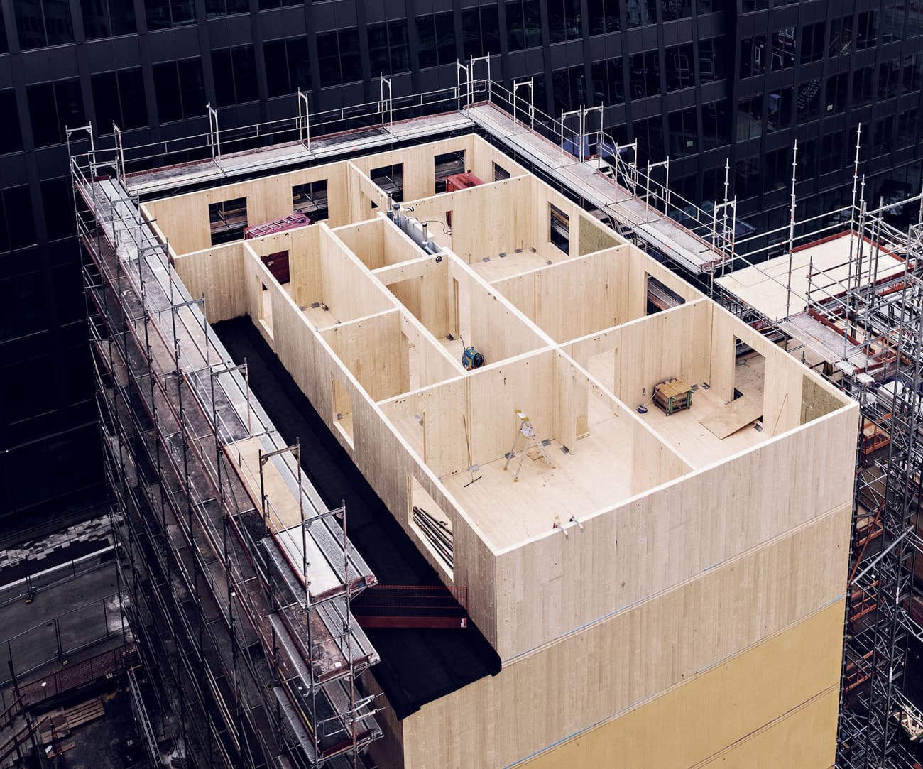 Architectural project - prefabricated, compact layout, natural materials, sustainable materials, wood, timber, scaffolding, cityscape, modular design, eco design, green building, neutral tones, construction site, under construction, urban development, urban environment, beige, brown, structural design, engineered wood, contemporary design, wood construction, timber building, innovative structure, timber panels, sustainable building, eco construction, CLT, cross laminated timber, circular construction, passive house, wood cladding, modern architecture, energy efficient, wooden facade, urban architecture, structural grid