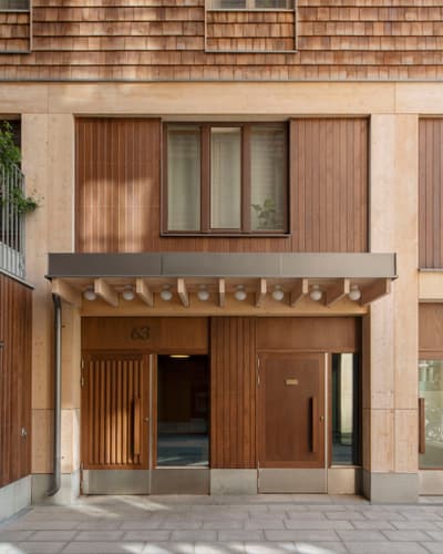 Architectural project - apartment facade, refined design, brown facade, timber canopy, minimal design, natural materials, architectural detail, city living, passive design, warm tones, eco design, city building, wood facade, timber facade, light wood, natural wood, honey wood, natural textures, sustainable building, large windows, timber cladding, architectural simplicity, modern architecture, energy efficient, inviting entrance, beige tones, glass windows, cozy exterior, wooden panels, wooden cladding, residential building, shingle facade, contemporary facade, modern exterior, vertical panels, residential facade, urban facade, urban housing
