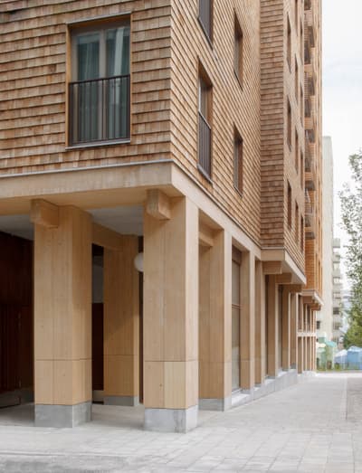 Architectural project - apartment block, apartment entrance, urban dwelling, urban residential, compact structure, textured exterior, communal living, natural materials, architectural detail, wood, timber, city living, passive design, sustainable design, warm tones, sustainable construction, urban landscape, beige, brown, concrete, light wood, daylight optimization, Scandinavian influence, minimalist design, timber detailing, eco building, wood panels, modern facade, timber cladding, modern architecture, Nordic style, cedar shingles, residential architecture, wooden facade, exterior wood, urban home, street view, contemporary building