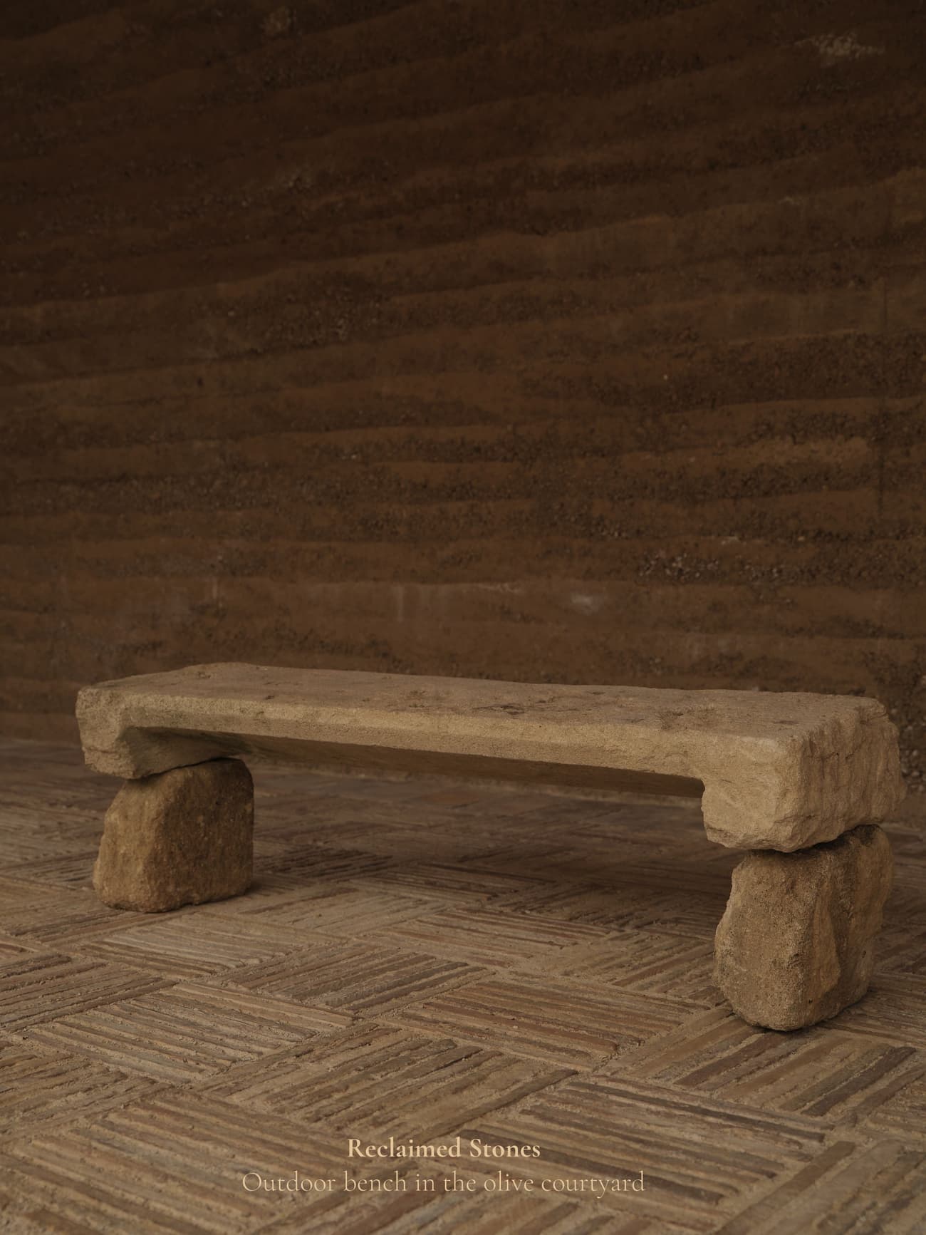 Architectural project - sustainability, natural stone, natural hues, rustic outdoor, rustic bench, stone bench, rugged texture, organic feel, rough finish, simple seating, courtyard seating, outdoor courtyard, versatile seating, weathered stone, garden bench, patio bench, primitive style, fired earth, raw materials, sustainable design, reclaimed materials, warm tones, beige, brown, eco friendly, compact space, natural setting, rustic charm, neutral palette, minimalist design, peaceful ambiance, earthy texture, rustic style, earthy tones, Mediterranean style, rural setting, tranquility, outdoor relaxation, outdoor bench, stone texture