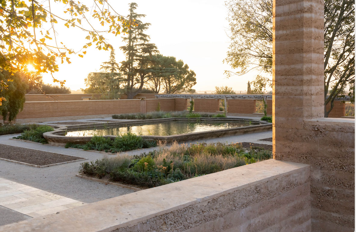 Architectural project - garden architecture, heritage design, rustic landscape, earth wall, terracotta walls, peaceful garden, garden courtyard, natural courtyard, reflective pool, mediterranean garden, mediterranean landscape, sunset view, classic landscape, architectural garden, historical influence, planting design, outdoor ambiance, sustainable courtyard, outdoor space, sustainable design, warm tones, eco design, exterior design, natural setting, rustic charm, serene space, outdoor seating, rammed earth, biophilic design, textured wall, stone, earthy tones, clay, environmental design, landscape design, greenery, tranquil atmosphere, sunlit, nature integration, open air, outdoor harmony, timeless design, water feature, courtyard, low impact design, outdoor relaxation