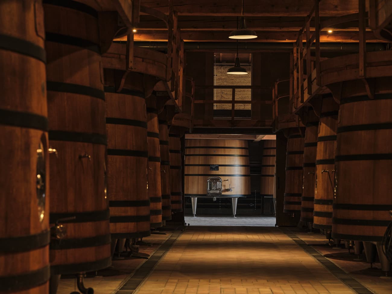 Architectural project - rustic interior, rich textures, oak wood, brick flooring, low light, industrial cellar, oak barrels, fermentation barrels, brewery vibe, wooden casks, fermentation room, industrial lighting, tiled floor, vintage industrial, cozy ambience, rustic floor, wine cellar, aged wood, warehouse feel, barrel storage, closed space, wine production, artisanal vibe, heavy duty, workshop atmosphere, craft brewing, brewing tradition, classic design, traditional look, brick interior, wooden planks, brown hues, intimate space, raw materials, warm tones, functional space, wood tones, wooden ceiling, industrial style, wooden beams, rustic charm, neutral palette, exposed wood, timber interior, heritage architecture, warm lighting, dark tones