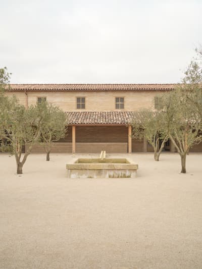 Architectural project - sturdy construction, tiled roof, minimalist landscape, terracotta roof, olive trees, Mediterranean courtyard, rustic house, mediterranean home, traditional facade, stone fountain, mediterranean architecture, pastoral environment, calming colors, harmonious setting, serene vibe, sustainable materials, outdoor space, natural light, outdoor living, eco friendly, farmhouse style, rustic charm, light brown, peaceful ambiance, neutral colors, tranquil setting, natural landscape, passive house, simple elegance, inviting entrance, beige tones, airy space, warm atmosphere, traditional design, classic architecture, exterior view, open air, gravel path, countryside house, textured facade, timeless design, plaster walls, simple lines, courtyard, rural retreat, clay tiles