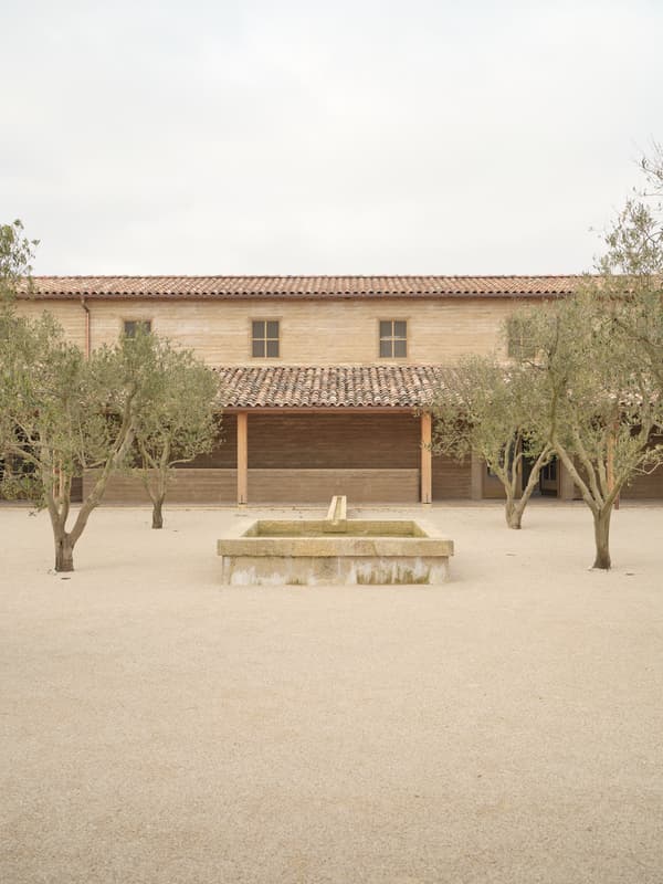 Architectural project - sturdy construction, tiled roof, minimalist landscape, terracotta roof, olive trees, Mediterranean courtyard, rustic house, mediterranean home, traditional facade, stone fountain, mediterranean architecture, pastoral environment, calming colors, harmonious setting, serene vibe, sustainable materials, outdoor space, natural light, outdoor living, eco friendly, farmhouse style, rustic charm, light brown, peaceful ambiance, neutral colors, tranquil setting, natural landscape, passive house, simple elegance, inviting entrance, beige tones, airy space, warm atmosphere, traditional design, classic architecture, exterior view, open air, gravel path, countryside house, textured facade, timeless design, plaster walls, simple lines, courtyard, rural retreat, clay tiles