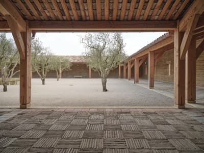Architectural project - timber columns, ambient light, pergola, rustic courtyard, tiled roof, earth walls, timber pergola, olive green, terracotta roof, olive trees, Mediterranean courtyard, rustic walls, textured ground, grid pattern, open courtyard, outdoor flooring, minimal design, natural materials, tranquil space, wood, timber, relaxation area, outdoor space, natural light, outdoor living, passive design, sustainable design, warm tones, exposed beams, gathering space, beige, exterior design, eco friendly, warm wood, rammed earth, earth tones, natural ventilation, rustic style, natural aesthetics, Mediterranean style, cozy outdoor, terracotta, landscape design, traditional style, peaceful vibe, earthy textures, open space, courtyard, wooden columns, garden space