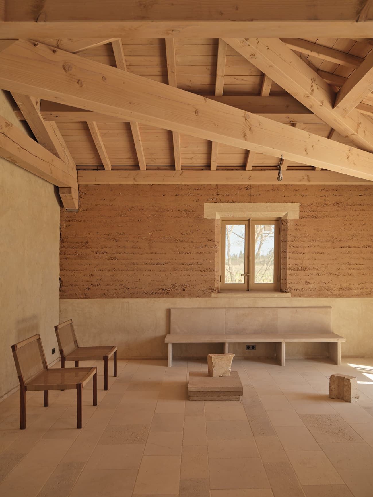 Architectural project - wooden chairs, rustic interior, clay walls, minimalist furniture, sitting area, country house, wooden construction, mud walls, vintage charm, traditional craft, serene vibe, indoor space, tranquil space, wood, timber, raw materials, natural light, passive design, sustainable design, warm tones, neutral tones, exposed beams, daylight, wooden ceiling, beige, light wood, low carbon design, eco friendly, wood beams, timber beams, minimalist design, eco materials, gathering area, rammed earth, natural palette, sustainable home, clean lines, architectural simplicity, window view, plaster, beige tones, rustic style, clay, handcrafted look, cozy atmosphere, artisanal design, warm light, plaster walls, earthy textures, natural insulation, serene interior, simple bench, rural retreat, earthy colors, farm style, residential interior