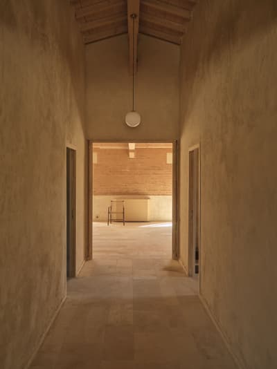 Architectural project - beige walls, light stone, wooden doors, rustic hall, narrow space, long corridor, southern charm, tranquil design, rustic minimalism, architectural warmth, understated chic, interior view, wood, timber, natural light, warm tones, neutral tones, exposed beams, beige, light wood, rustic modern, natural textures, serene atmosphere, peaceful setting, wooden floor, minimalist design, relaxed atmosphere, clean lines, simple elegance, cozy vibe, plaster, timber ceiling, warm ambiance, inviting space, earthy tones, Mediterranean style, textured walls, bright interior, plaster walls, warm lighting, soft light, corridor, hallway, pendant lamp, vaulted ceiling