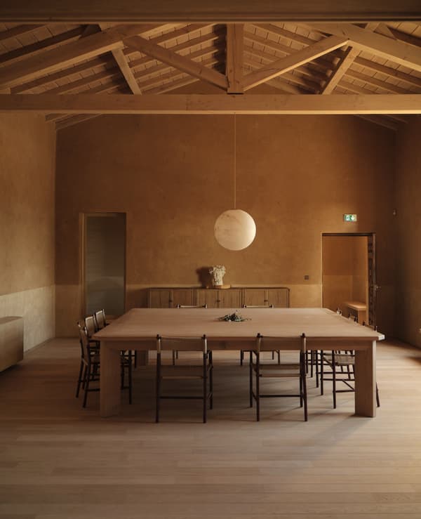 Architectural project - open ceiling, communal dining, dining chairs, modern farmhouse, rustic dining, pendant lighting, open dining, minimalist dining, spherical pendant, large table, spacious room, monochromatic, farmhouse vibe, warm interior, indoor space, natural materials, natural light, sustainable design, warm tones, daylight, gathering space, beige, light wood, eco friendly, farmhouse style, simple design, honey wood, wood beams, timber beams, intimate setting, Scandinavian style, timber floor, neutral colors, social space, wood floor, timber elements, modern rustic, passive house, architectural details, wooden table, inviting space, cozy atmosphere, Nordic vibe, textured walls, earthy palette, wooden textures, plaster walls, interior design, relaxed ambiance