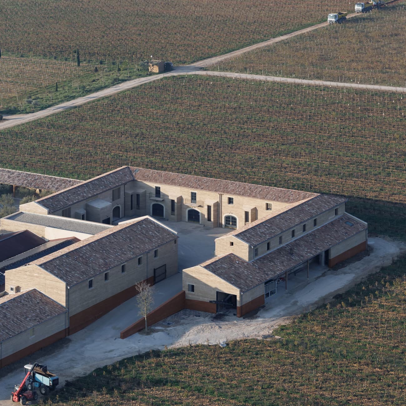 Architectural project - beige stone, rural landscape, terracotta tiles, countryside vibe, historic influence, heritage style, wine production, classic design, vineyard estate, pastoral setting, winery building, courtyard layout, farm setting, agricultural site, winery facility, stone construction, agricultural architecture, enclosed courtyard, farm complex, southern architecture, vintage winery, production site, storage buildings, regional building, wine estate, farming operations, vineyard operations, open site, rural ambience, winery design, agricultural function, sustainable approach, wine architecture, outdoor space, warm tones, rural architecture, rustic charm, neutral palette, earthy tones, pitched roof, brick facade, traditional style, natural surroundings, expansive view, brown brick
