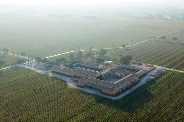 Architectural project - stone facade, rural landscape, brickwork, agricultural building, outdoor environment, terracotta roof, regional architecture, wine production, vineyard, winery, agricultural setting, vineyard estate, winery complex, vineyard facility, scenic location, open field, farm land, vineyard rows, eco farming, sustainable agriculture, scenic design, pastoral setting, traditional materials, agrarian design, spacious exterior, agricultural typology, rural aesthetics, outdoor space, landscape architecture, rural architecture, rustic vibe, rustic charm, serene atmosphere, sustainable building, earth tones, natural colors, stonework, pitched roof, countryside architecture, traditional design, brick facade, heritage building, natural environment, gable roof, heritage architecture, aerial view, calm setting, countryside setting, clay tiles, farm style, expansive view