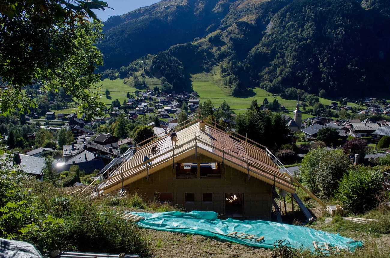 Architectural project - ecological home, forest backdrop, open surroundings, scenic setting, nature views, hillside home, home building, natural materials, wood, timber, sustainable design, green building, under construction, construction process, building site, landscape architecture, wooden beams, timber construction, rural architecture, rustic vibe, outdoor, exterior, tranquil setting, eco building, residential construction, blue sky, framing, natural landscape, low carbon, modern rustic, biophilic design, sustainable home, scenic view, wood frame, panoramic view, pitched roof, rural setting, countryside, nature integration, countryside living, cabin style, wooden structure, passive solar, cozy home